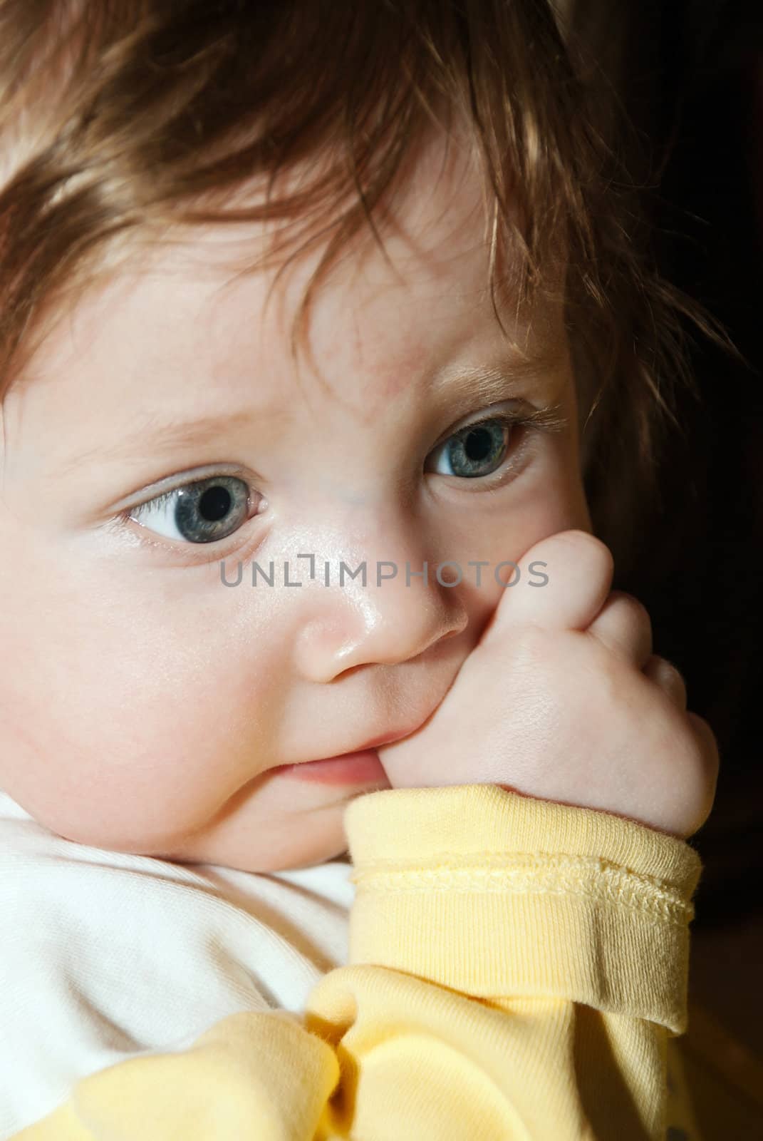 Close-up portrait of a happy boy with his finger in his mouth. Soft focus