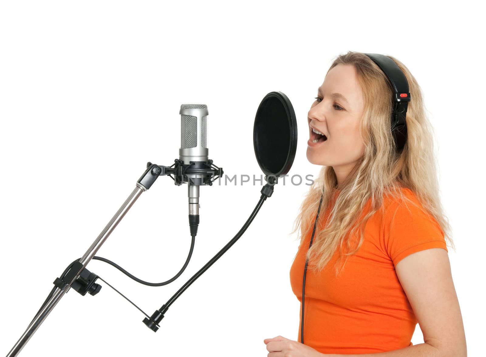 Female singer in orange t-shirt singing with studio microphone. Isolated on white background.
