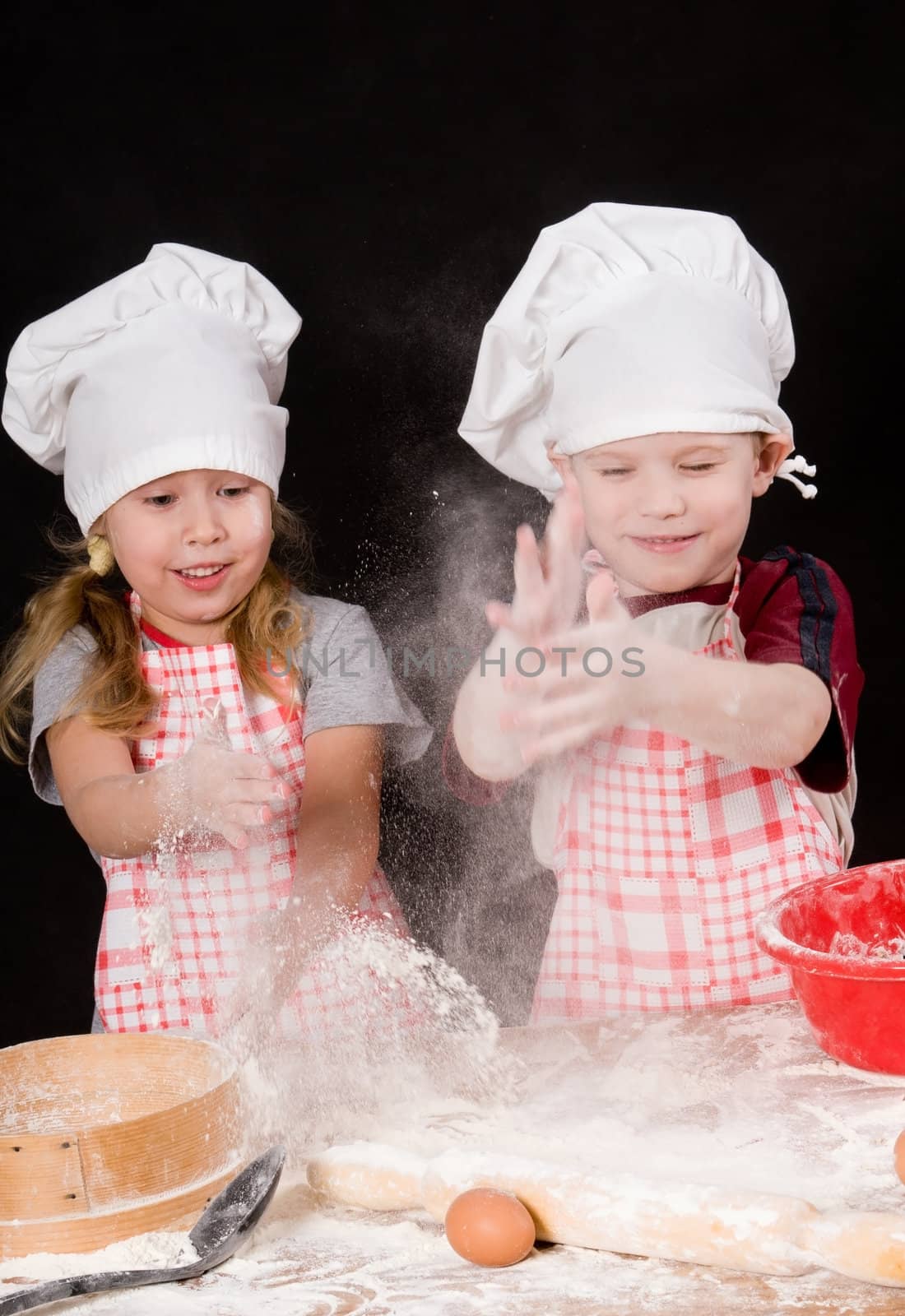 Two children plays with the flour on dark background