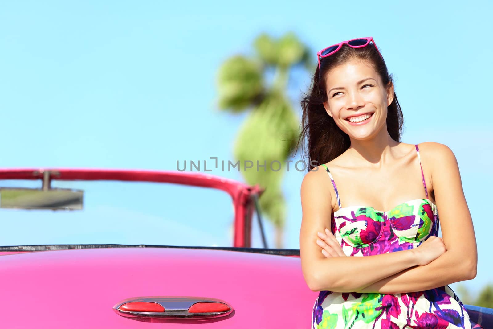 Car woman happy smiling by pink vintage car. Beautiful young multiracial female driver in Havana, Cuba.