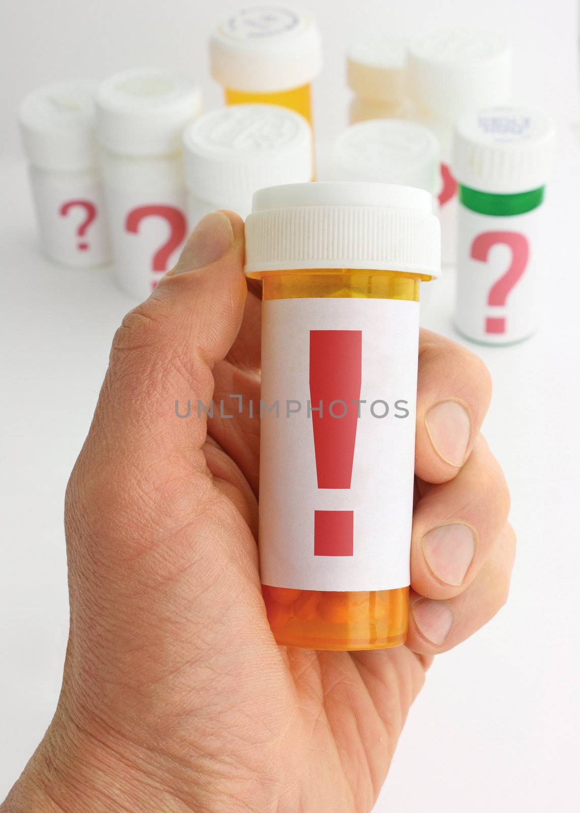 A hand holding a medicine bottle marked with a large exclamation mark. Several additional pill bottles, all labeled with large question marks, are in the background. The Image uses a shallow depth of field and background is moderately out of focus.