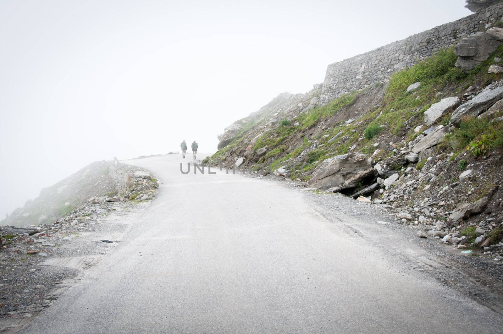 Two man on a mountain road in mystic fog
