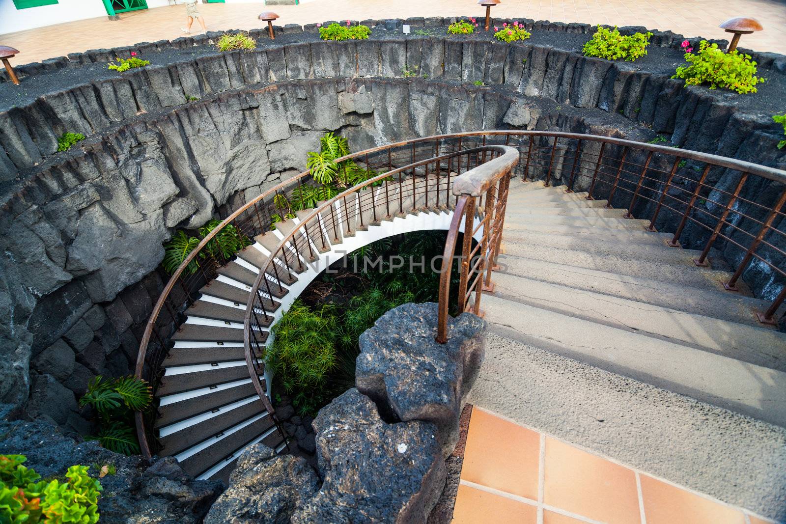 Stone spiral staircase with flowers in modern interior.