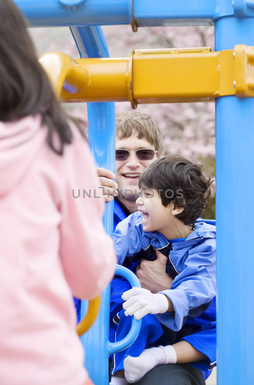 Father playing at playground with disabled son who has cerebral palsy