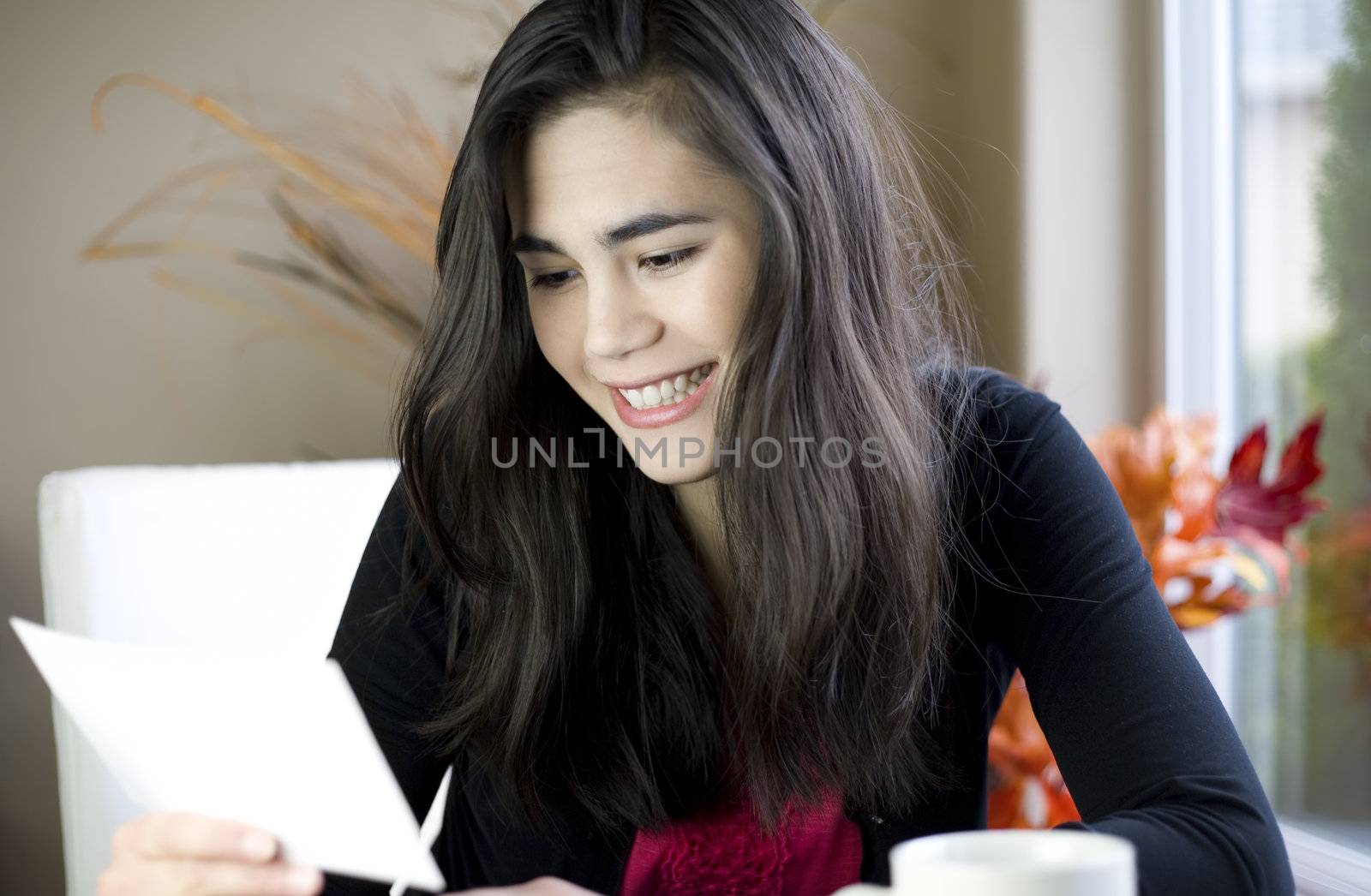 Teenage girl or young woman happily reading note in hand