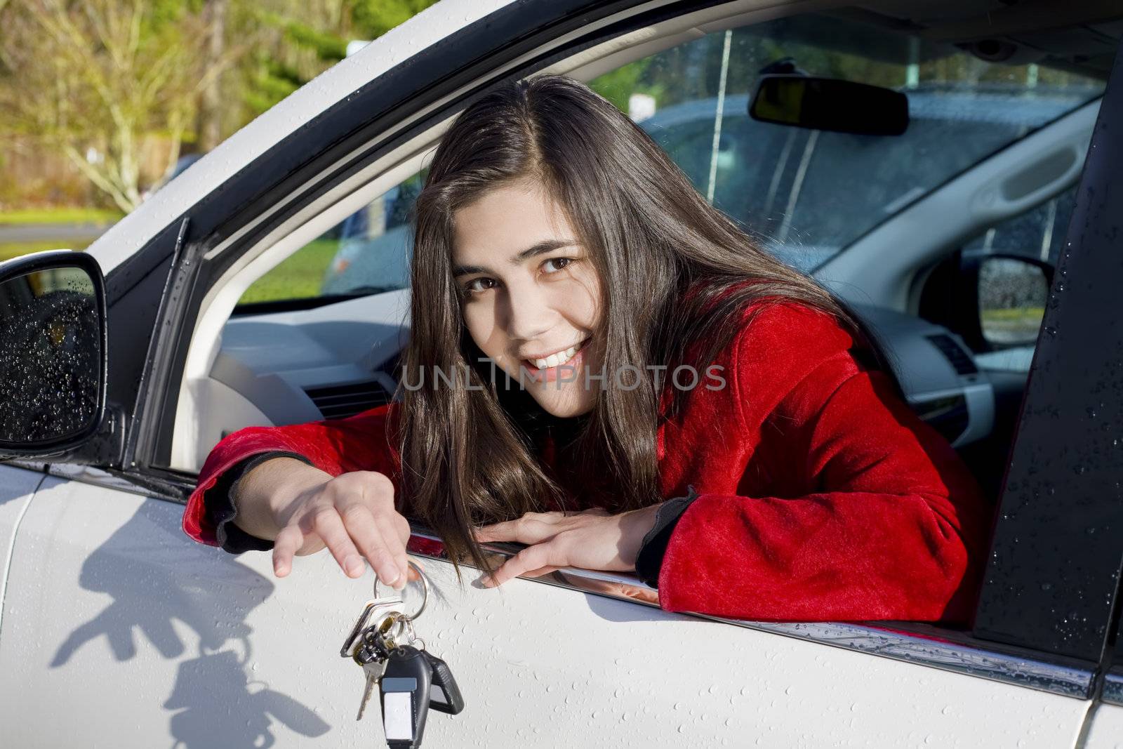 Beautiful biracial teenage girl in driver's seat holding keys to white car