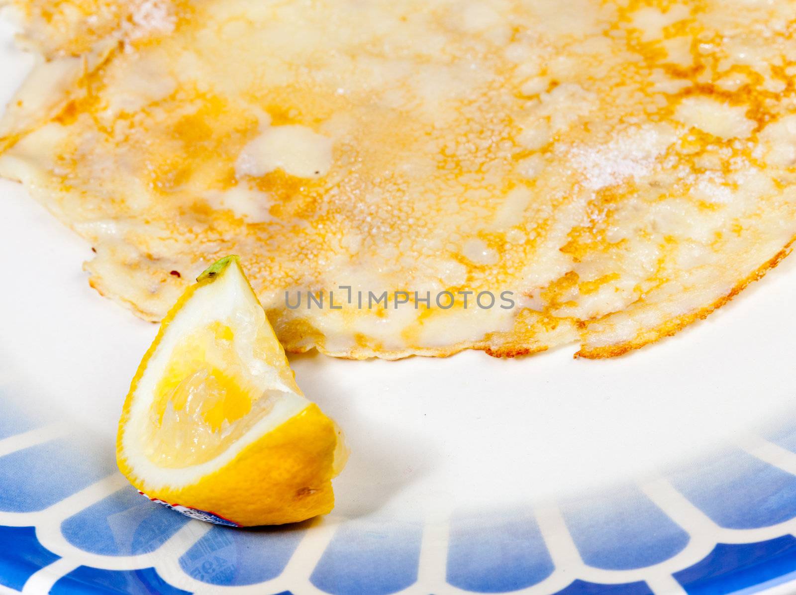 Cooked homemade pancake and lemon on blue plate