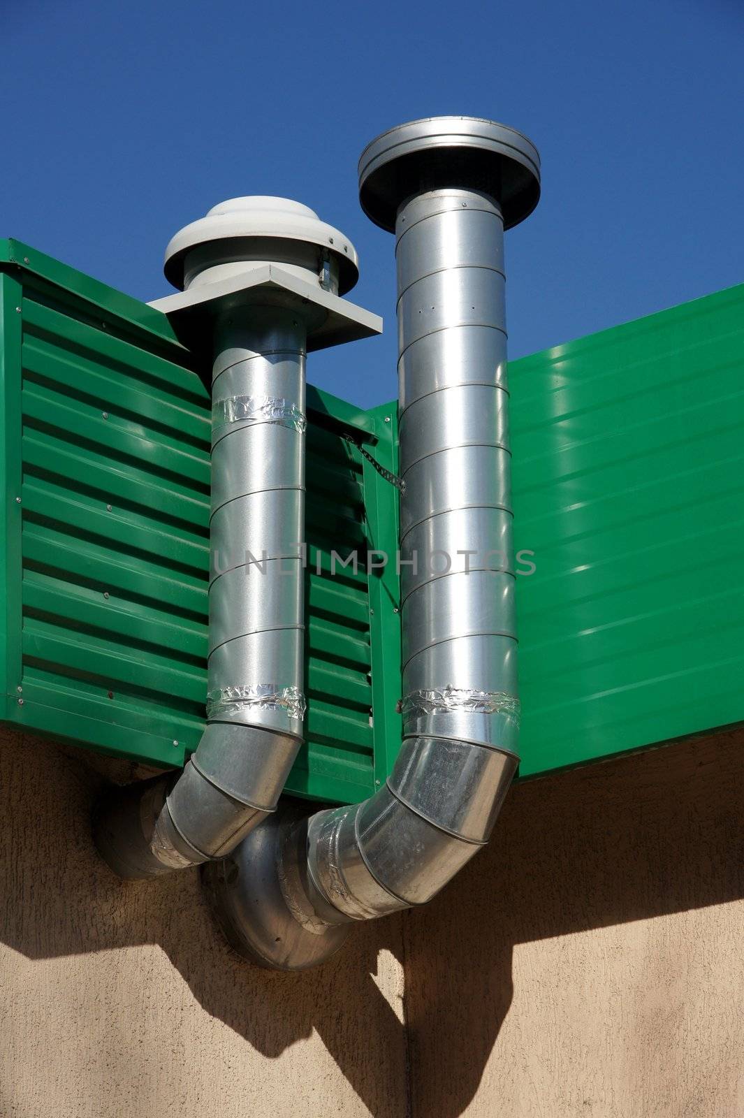 Pipes of ventilation are located on a wall of a building