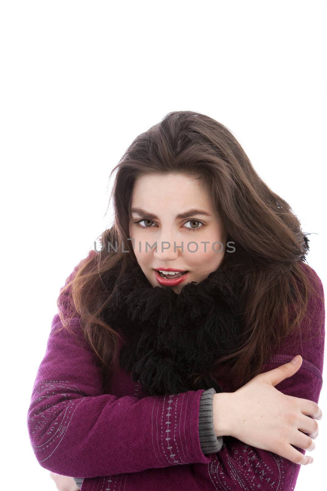 Beautiful cold woman in winter clothing standing hugging herself around the arms isolated on white