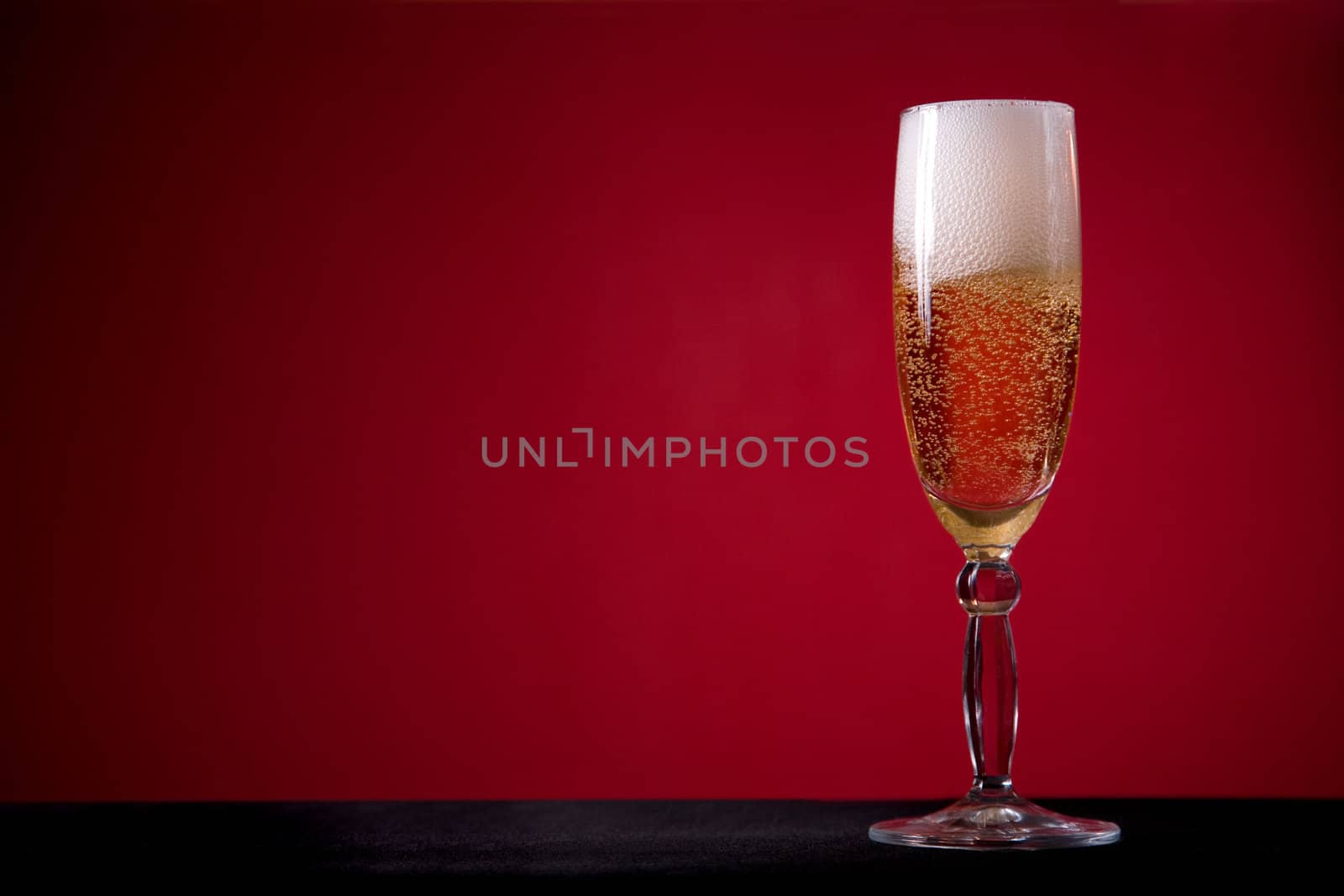 Champagne glass over red background, lot of copy-space 