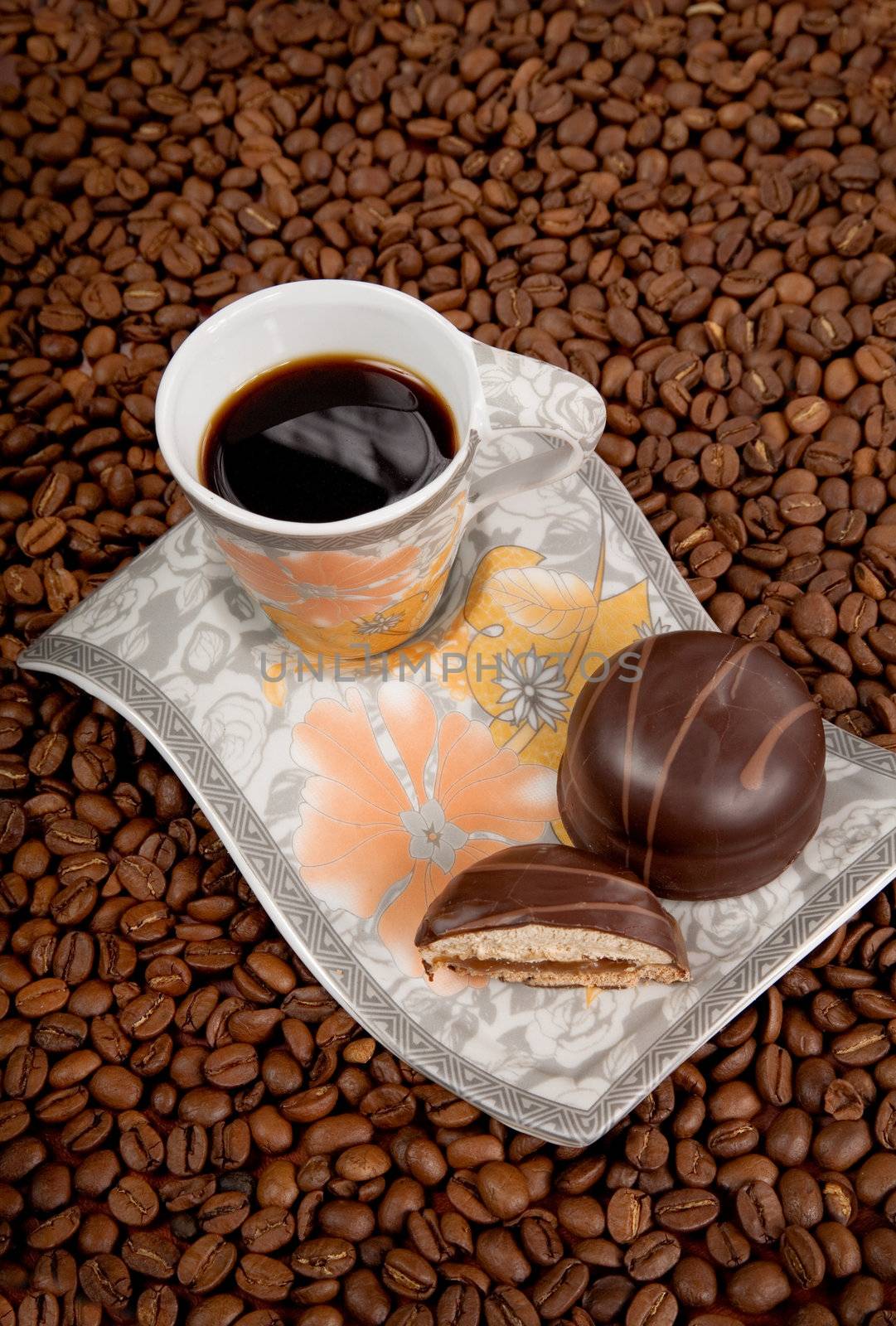 Coffee cup with candies on beans background, high angle view 