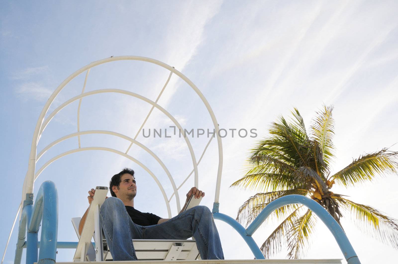Young boy sitting on chair against tropical sky background