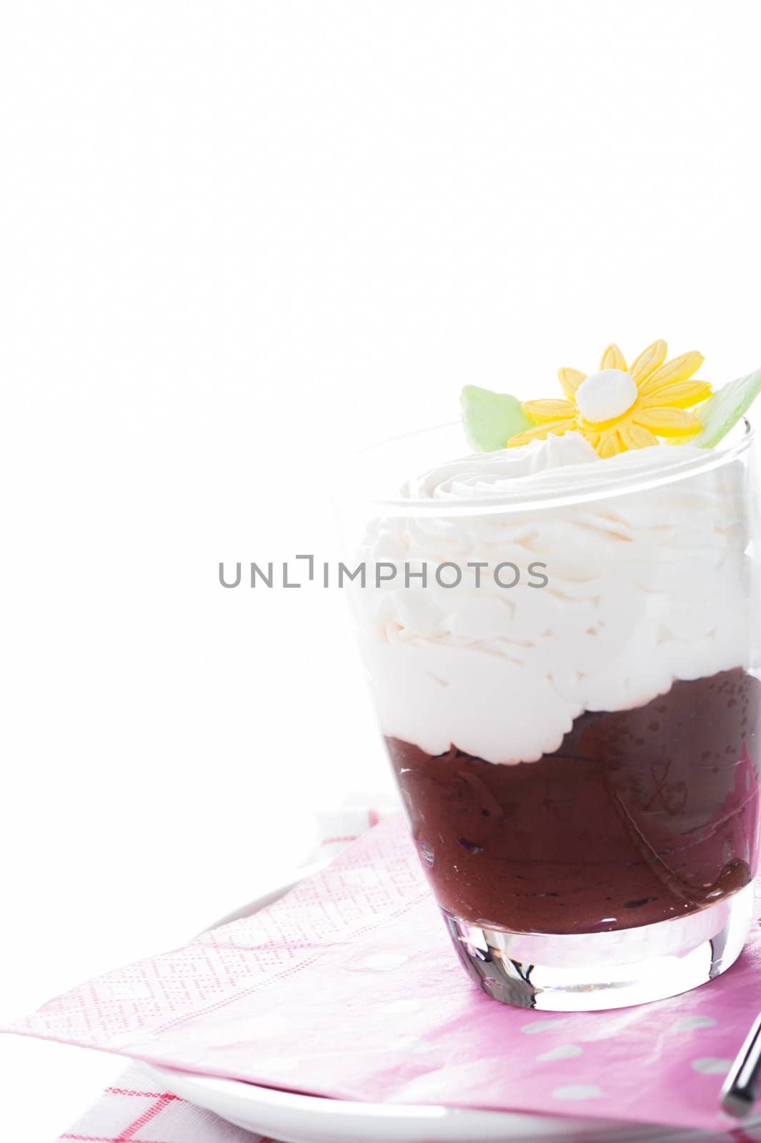 A glass with mousse au chocolat and whipped cream on white background as a studio shot