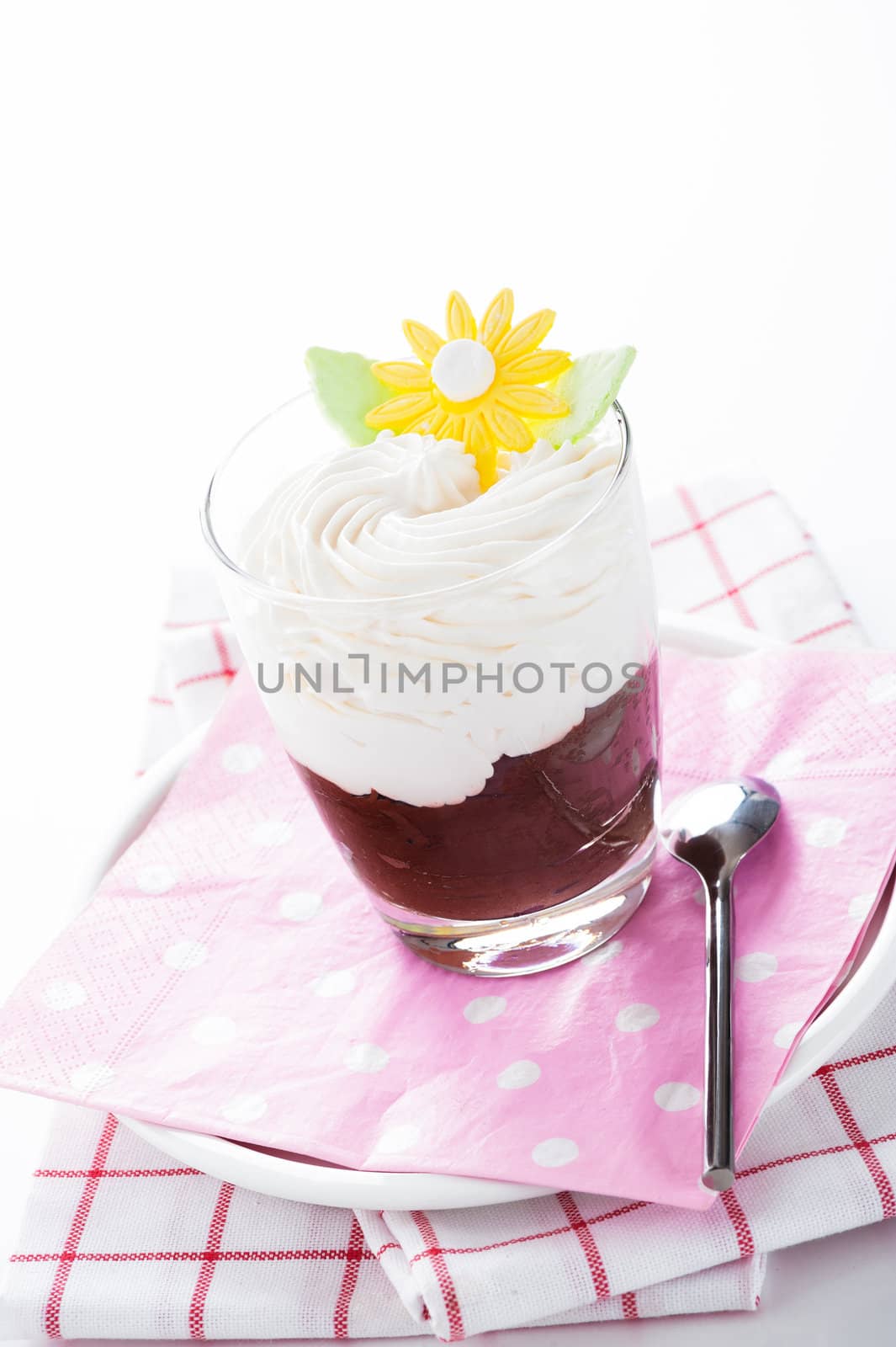 A glass with mousse au chocolat and whipped cream on white background as a studio shot