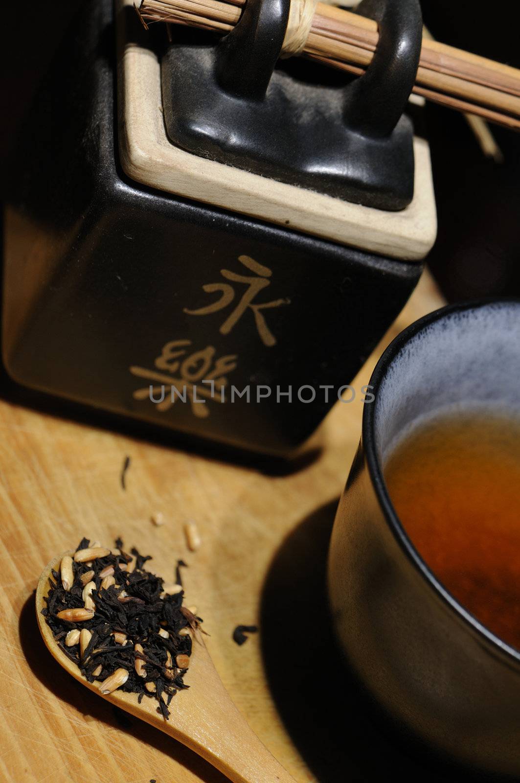 Asian black tea set with rice grains over wood background