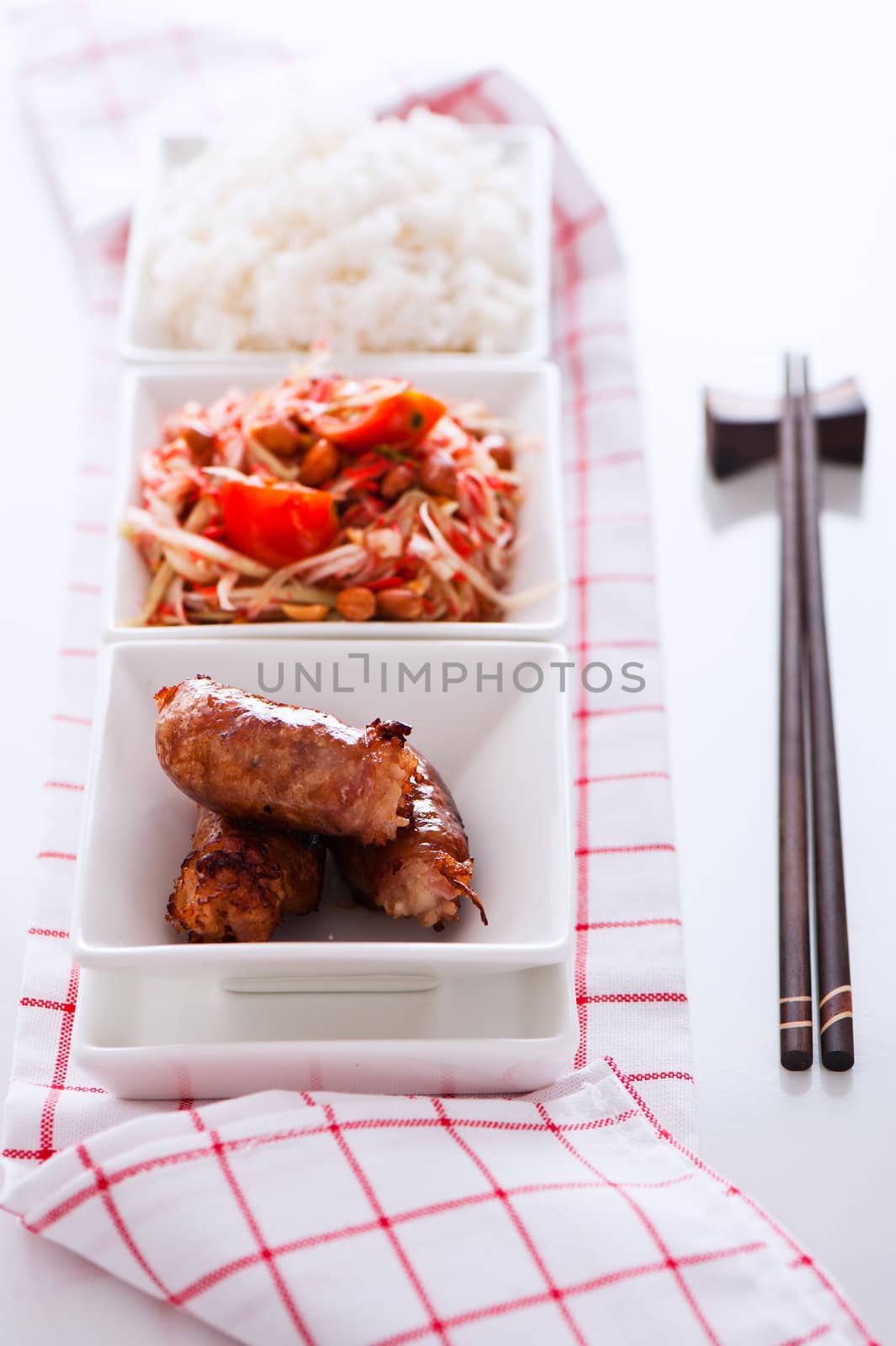 Spicy thai papaya salad with sausage and rice on white background as a studio shot