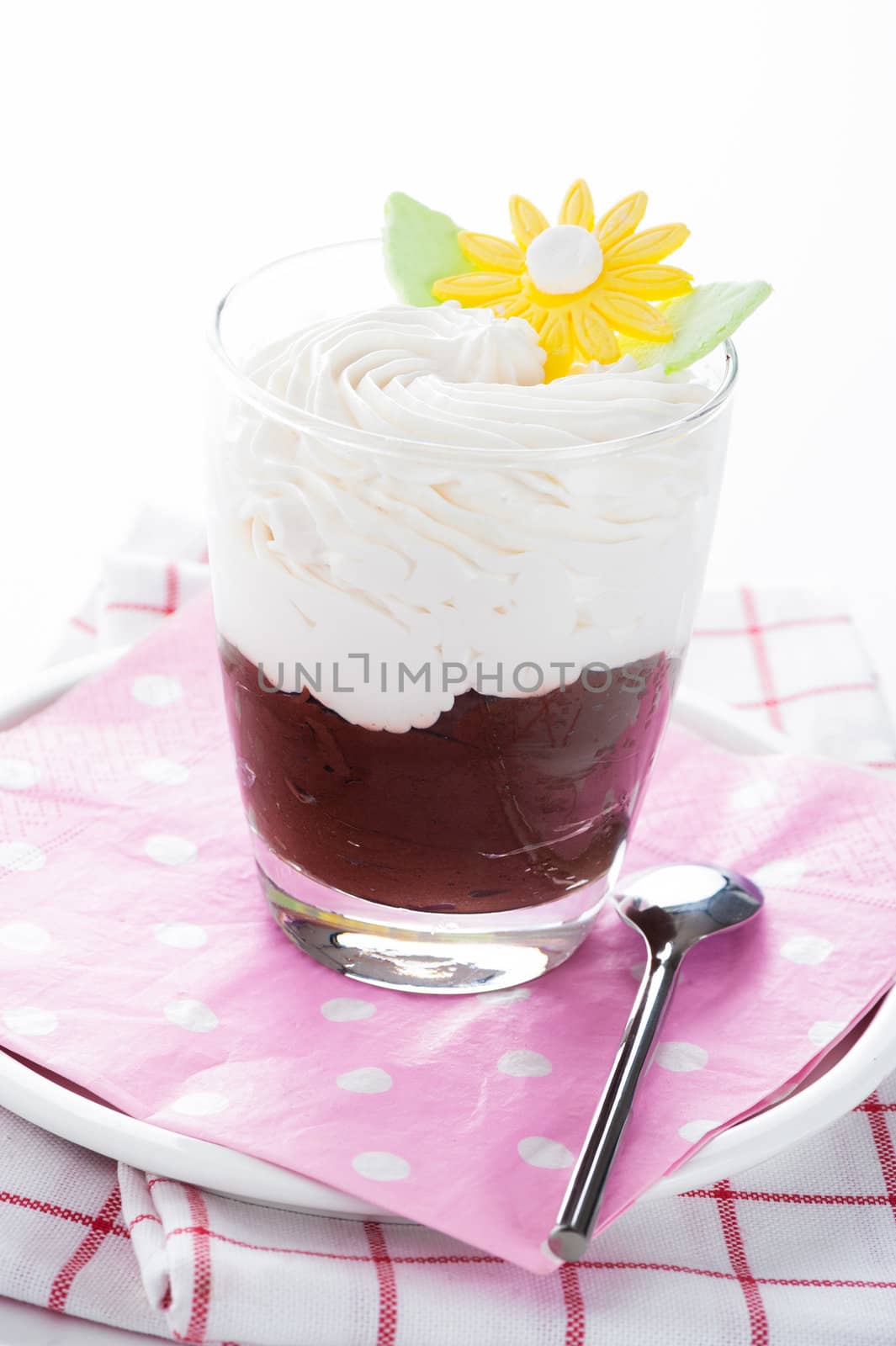 A glass with mousse au chocolat and whipped cream on white background as a studio shot