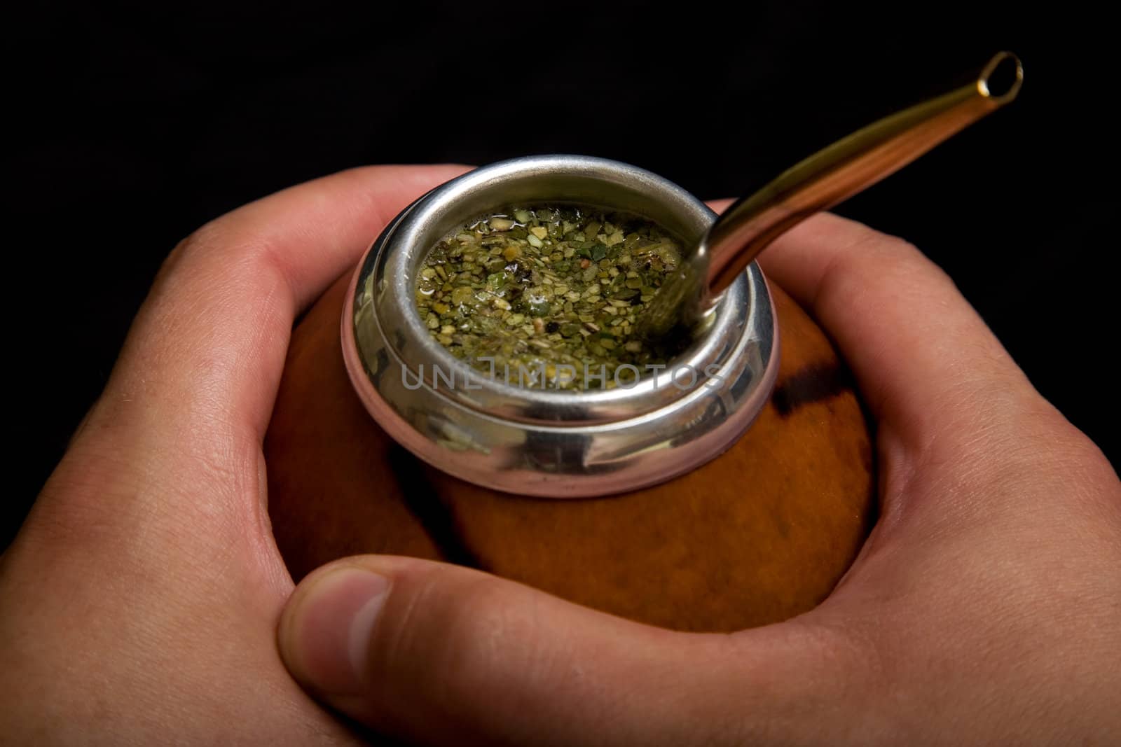 Male hands holding Argentinean Calabash with Bombilla, selective focus on mate 