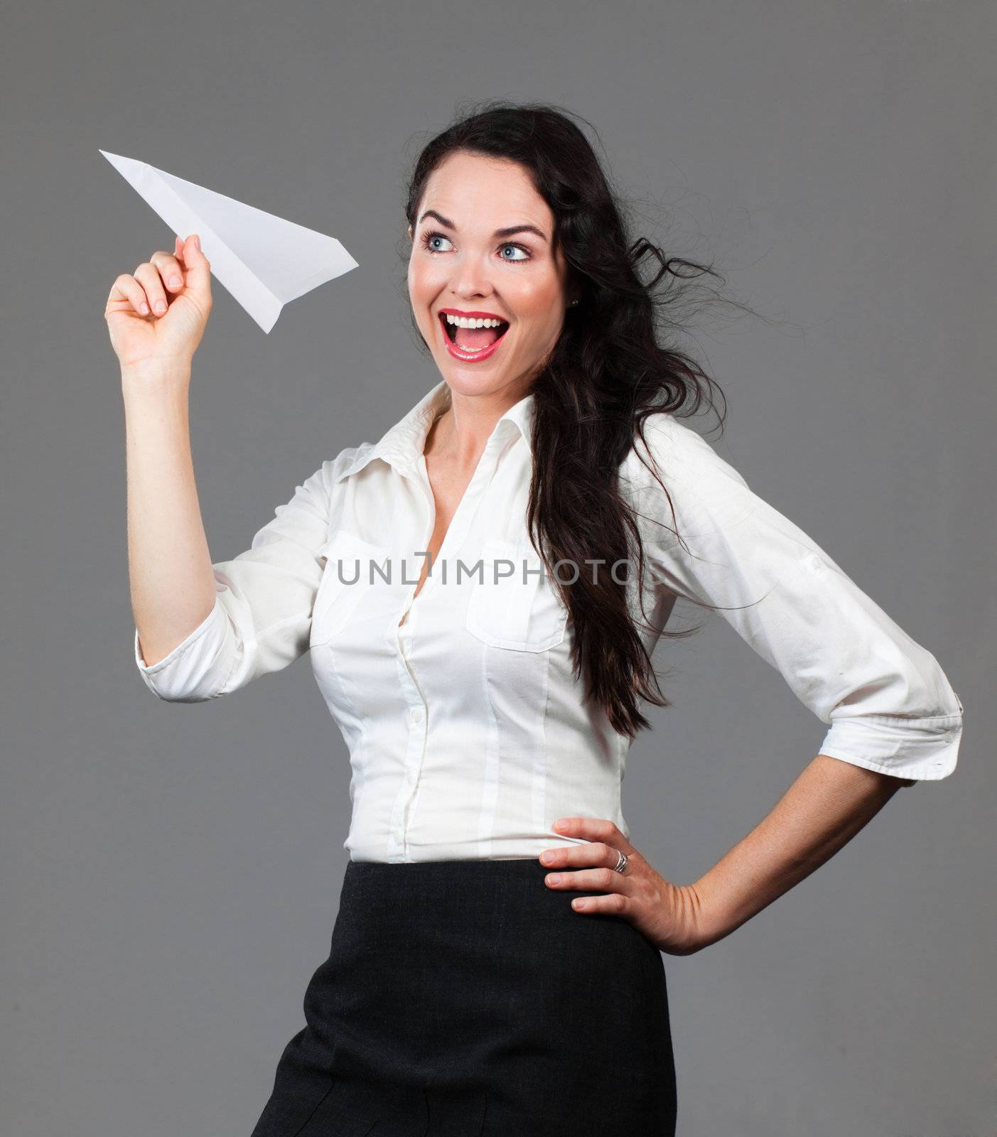 Beautiful young business woman holding a paper airplane smiling