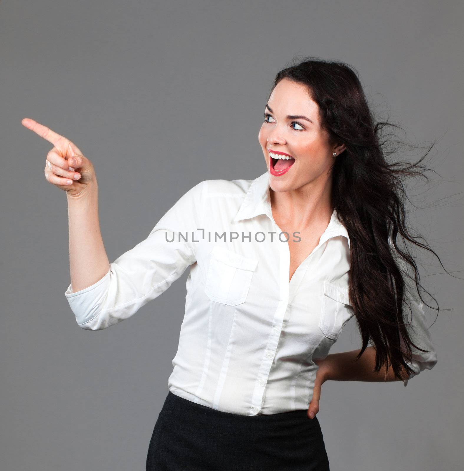 Beautiful young smiling business woman pointing to copyspace