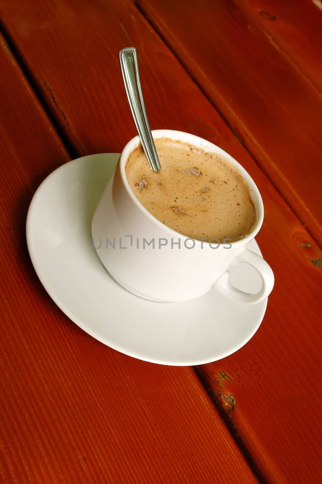 Cappuccino cup with spoon on wood background