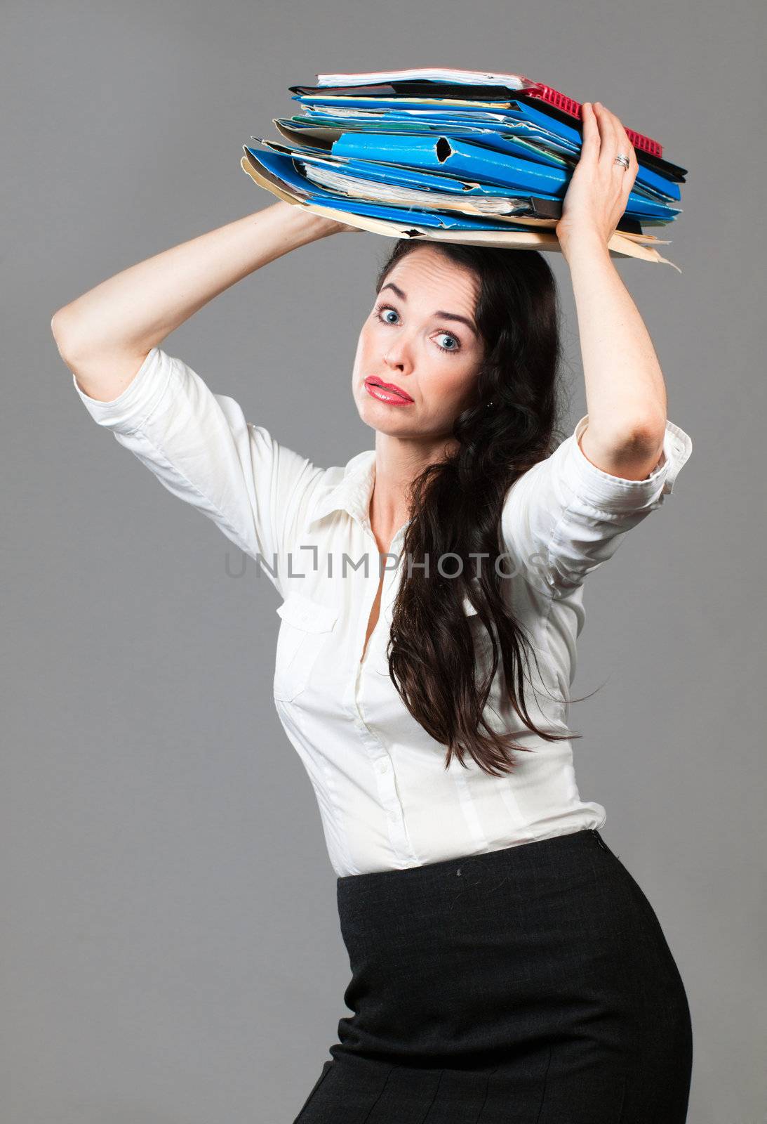 Portrait of a tired and overworked business woman carrying paperwork on her head