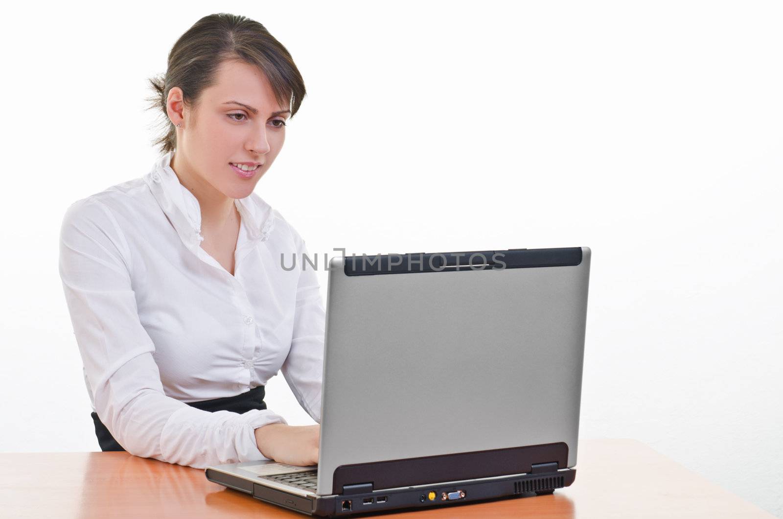 Young business woman sitting at desk and typing on laptop, high key, focus on eyes