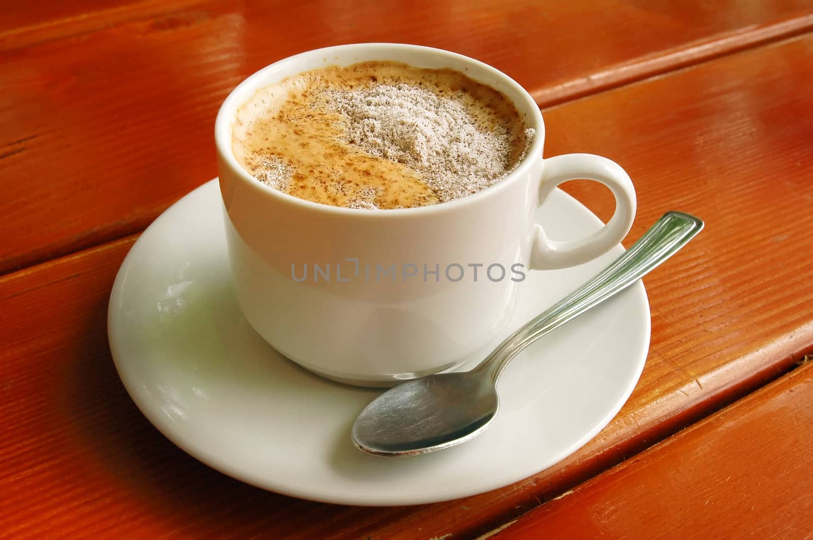 Cappuccino cup with metal spoon on wood background