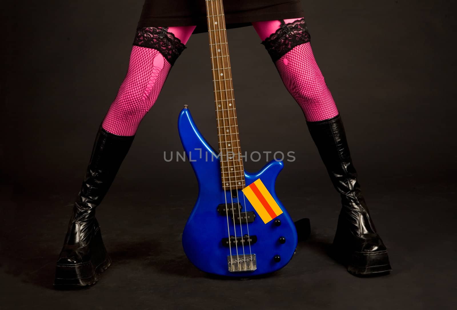 Close-up of woman legs with bass guitar isolated in studio