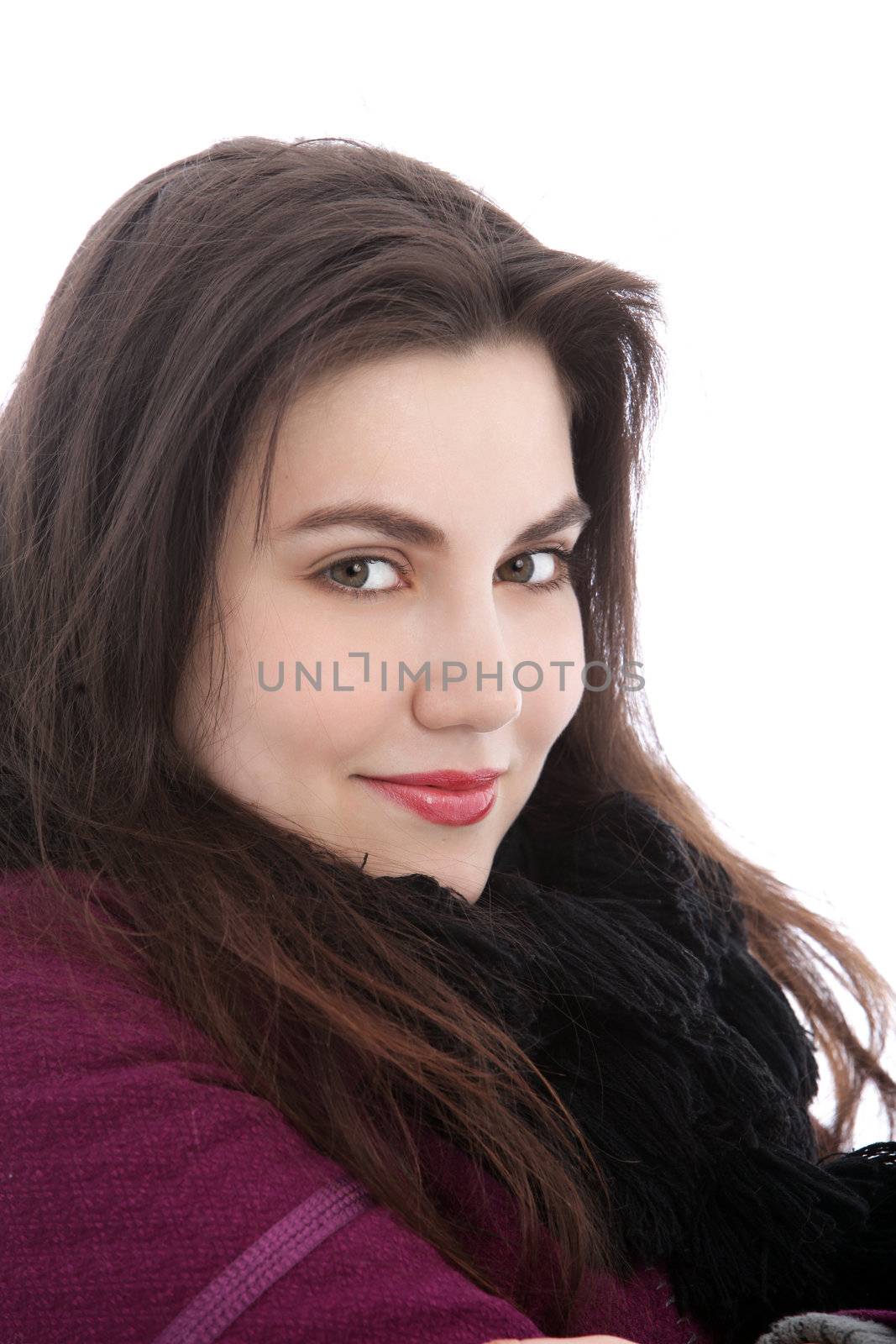 Smiling attractive young brunette woman in warm winter clothing looking sideways at the camera isolated on white