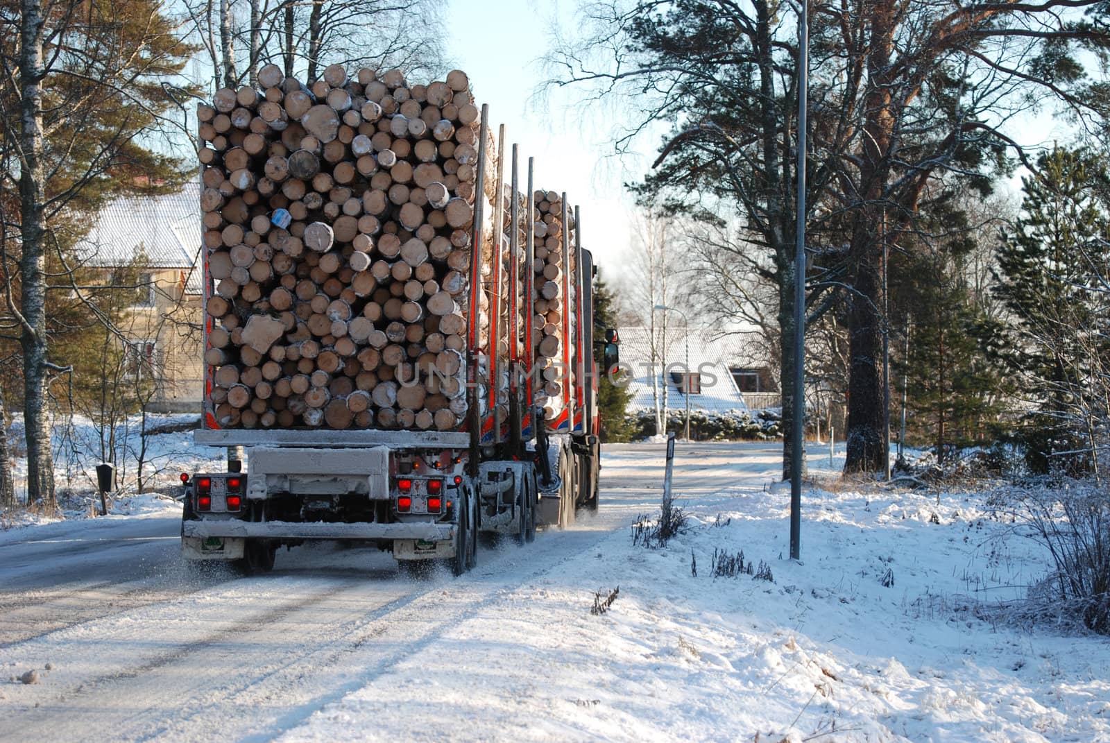 A Truck with timber driving on a small road