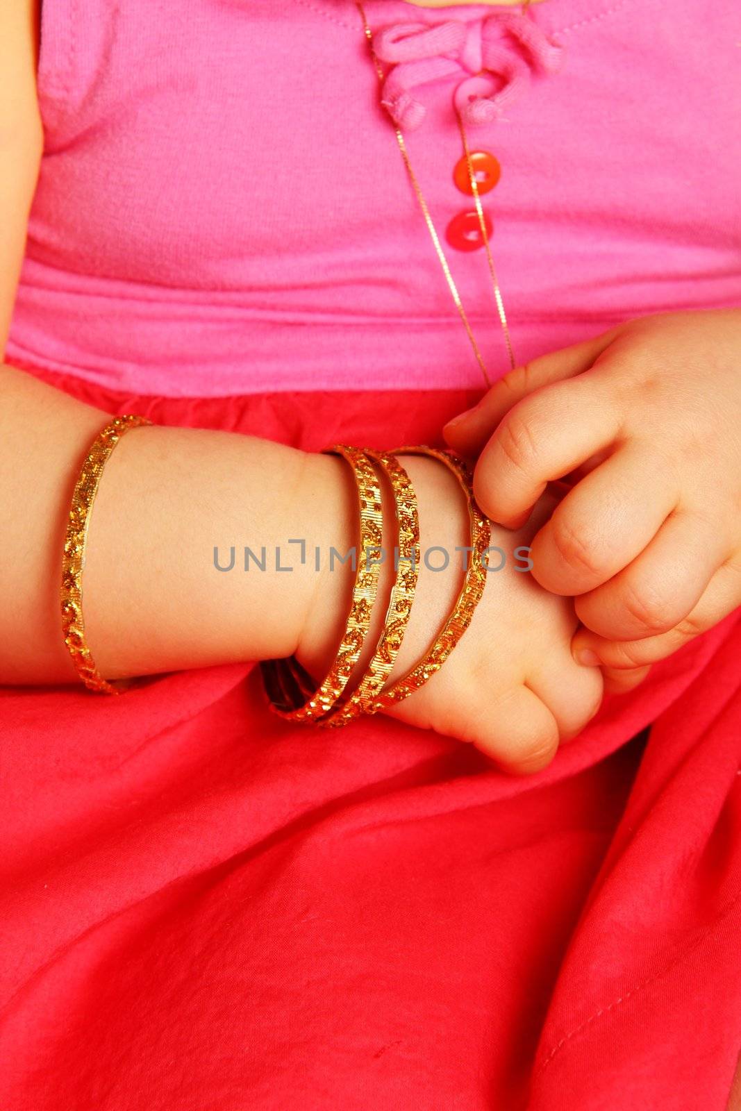 Baby hands, with a golden bracelet, isolated towards dark red