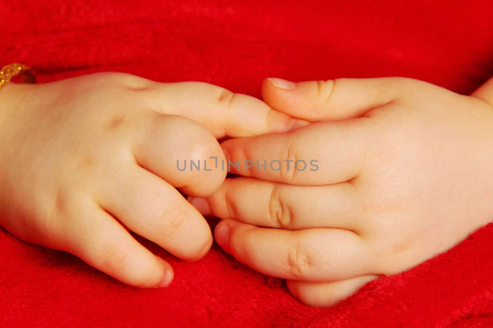 Baby holding hands, isolated towards dark red