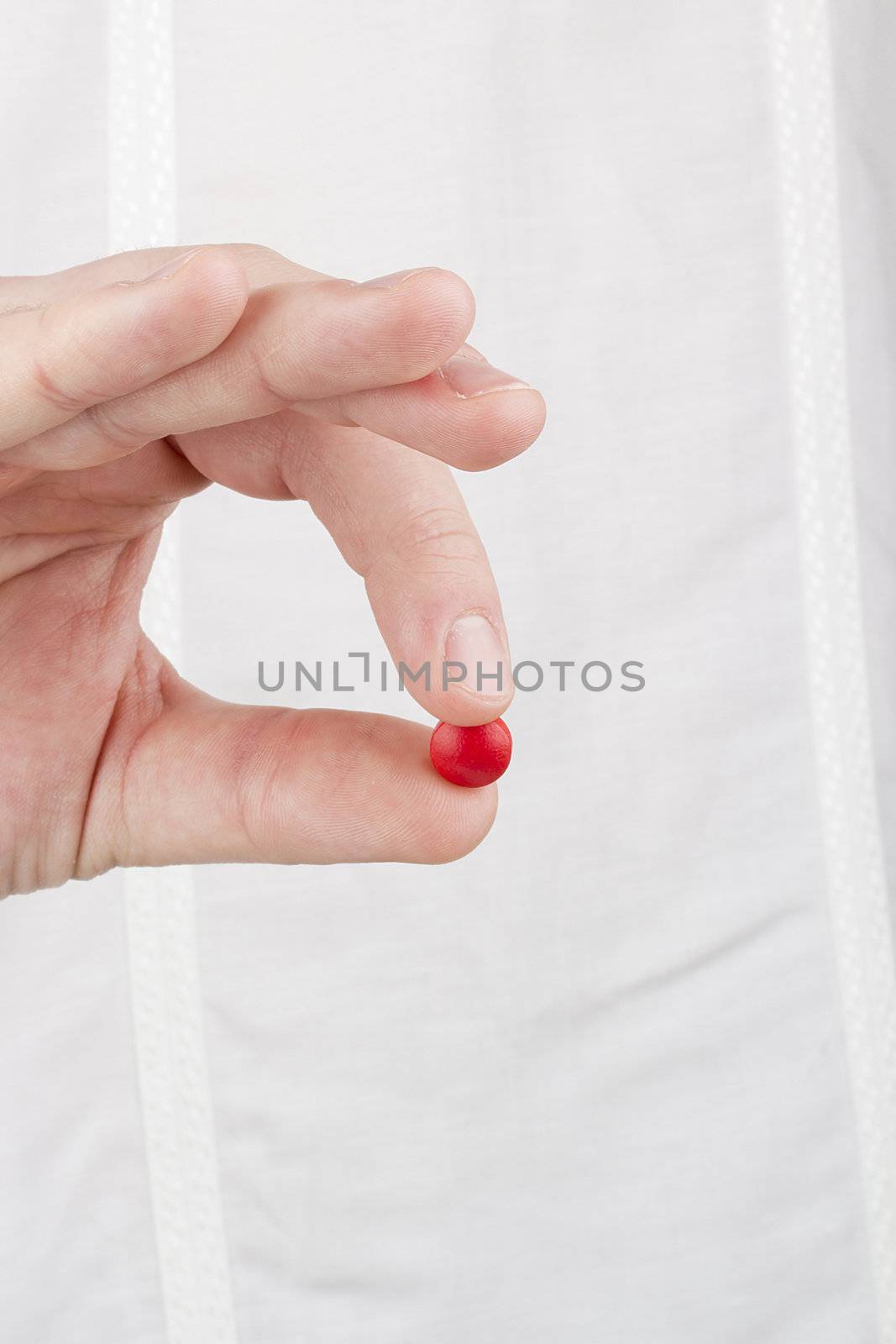 Close-up photograph of a hand holding a red tablet.