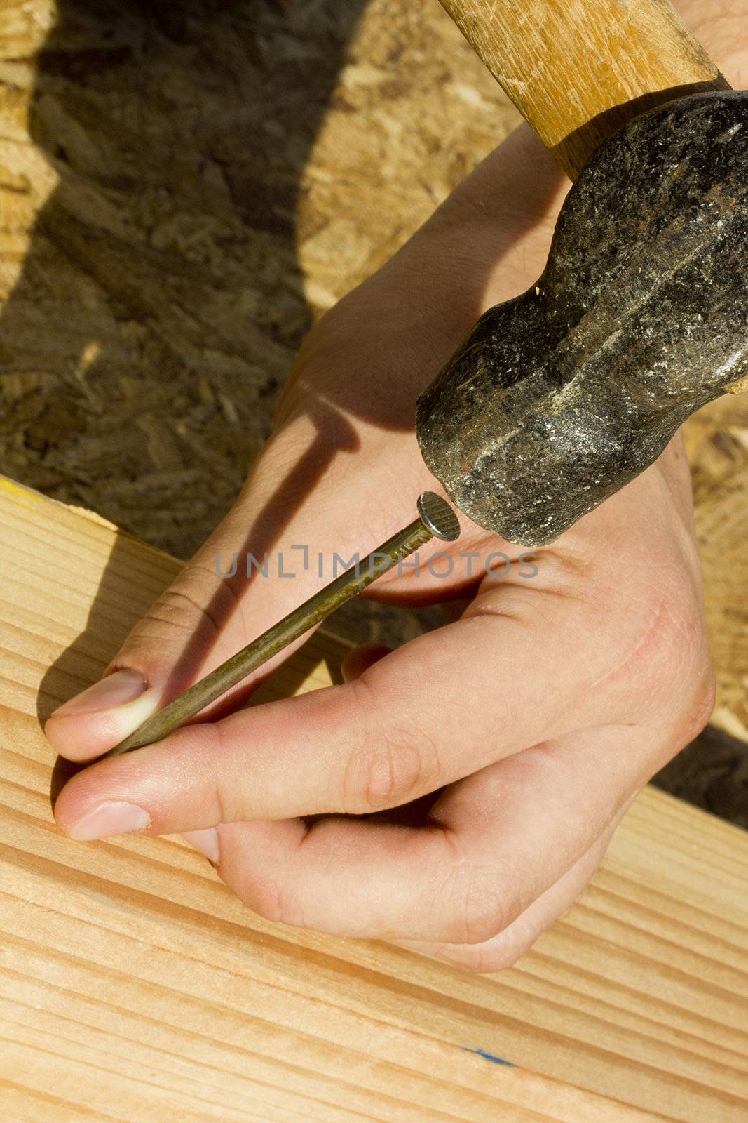 Construction worker hammering a nail into a piece of wood.