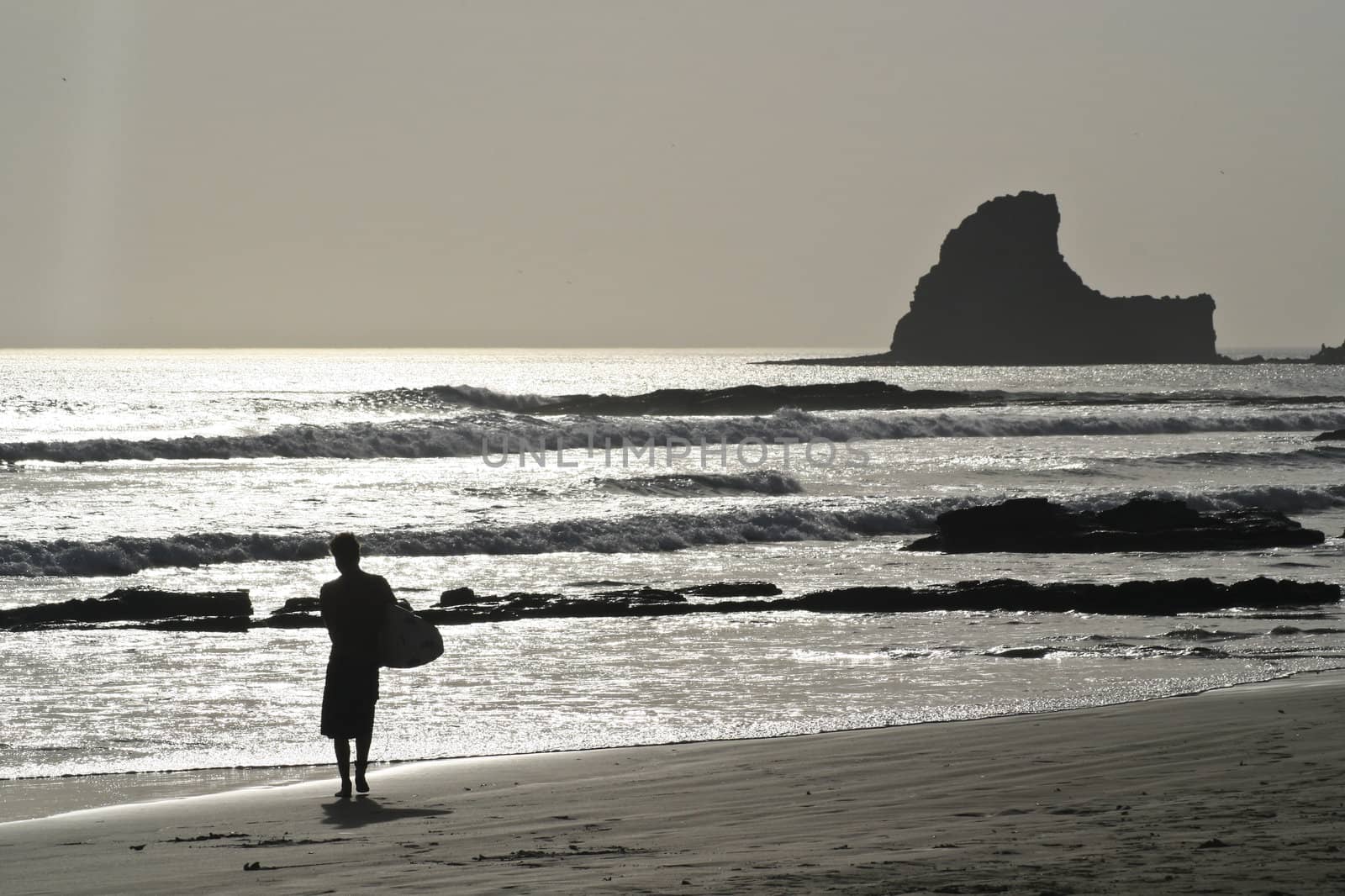 A surfer carries his board at a beach near San Juan del Sur.