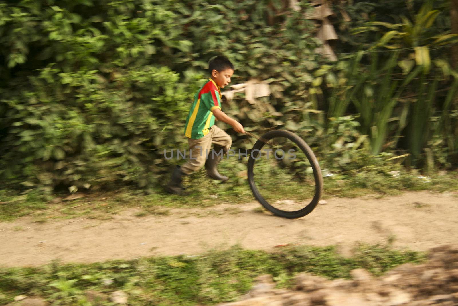 A boy is playing with a bicycle tyre in the countryside in Nicaragua.