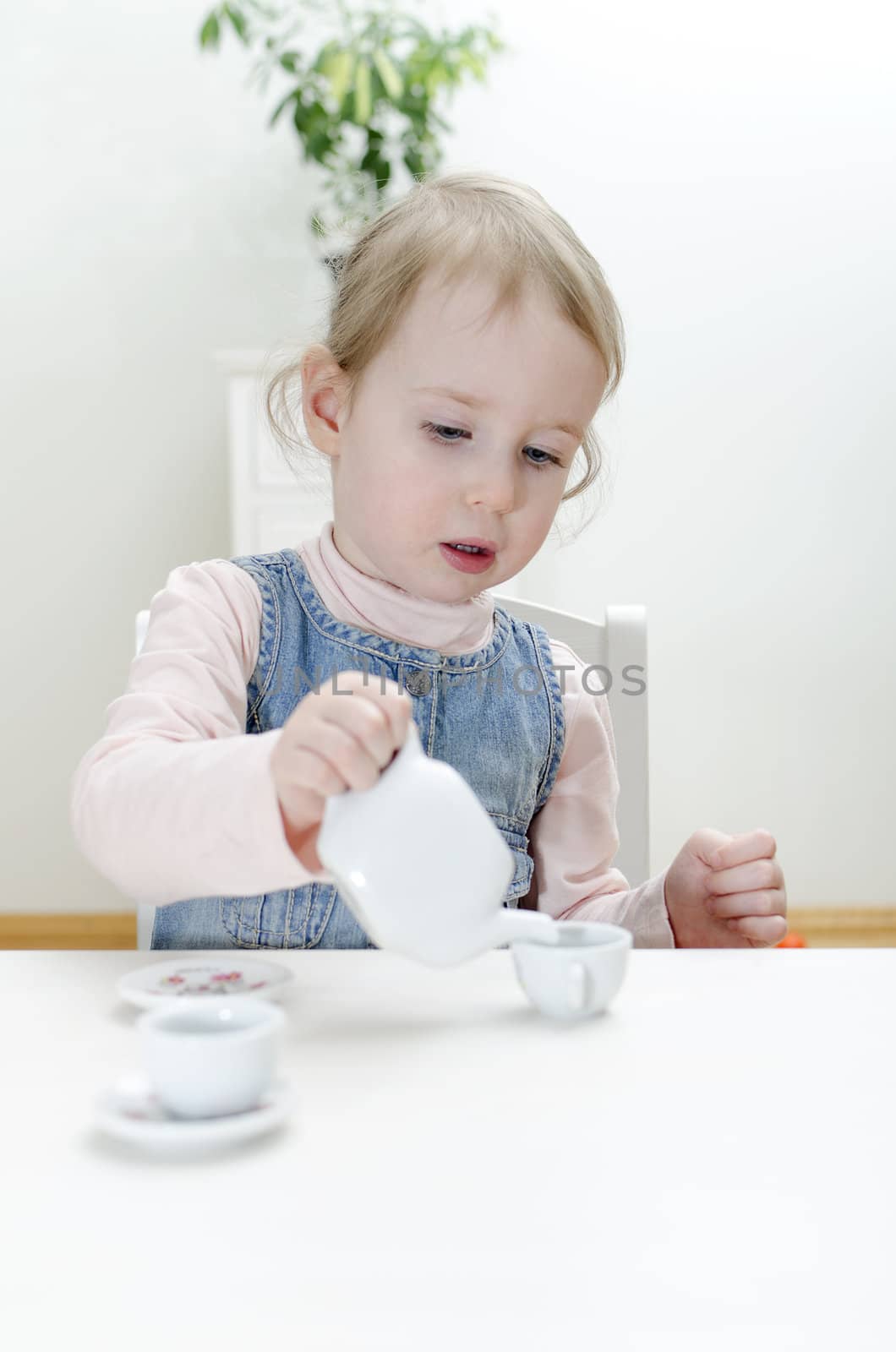 Cute little girl drinks tea at home.