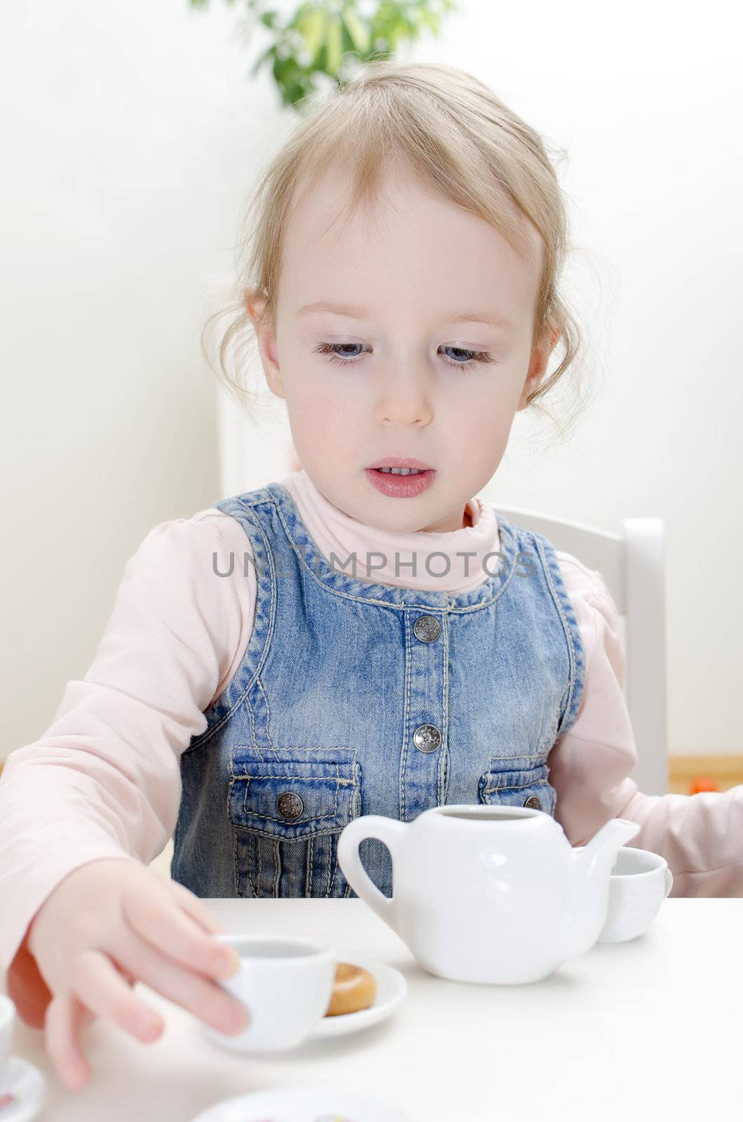 Cute little girl drinks tea with bagel