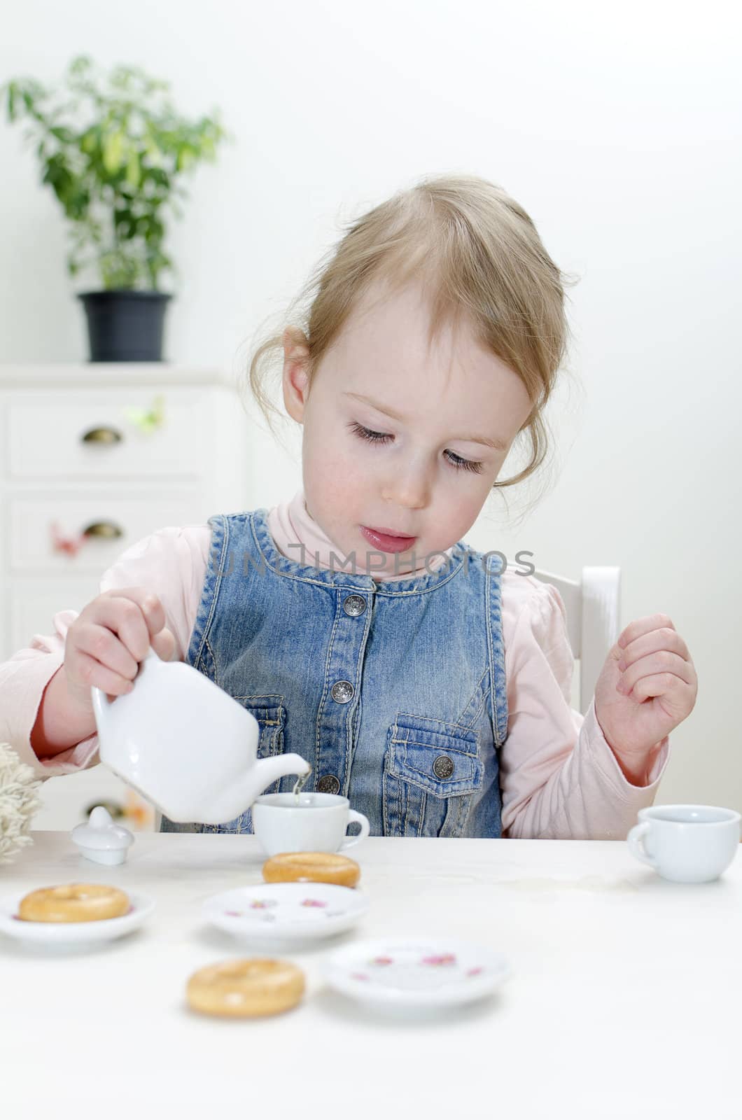 Cute little girl drinks tea with bagels