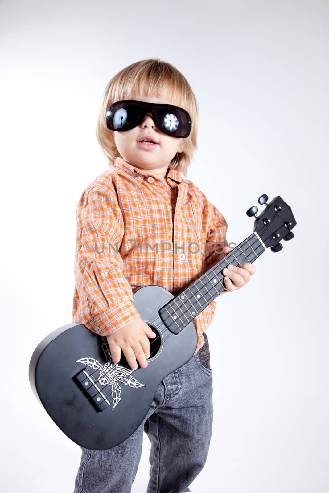 Cute little boy with ukulele guitar, studio shot 