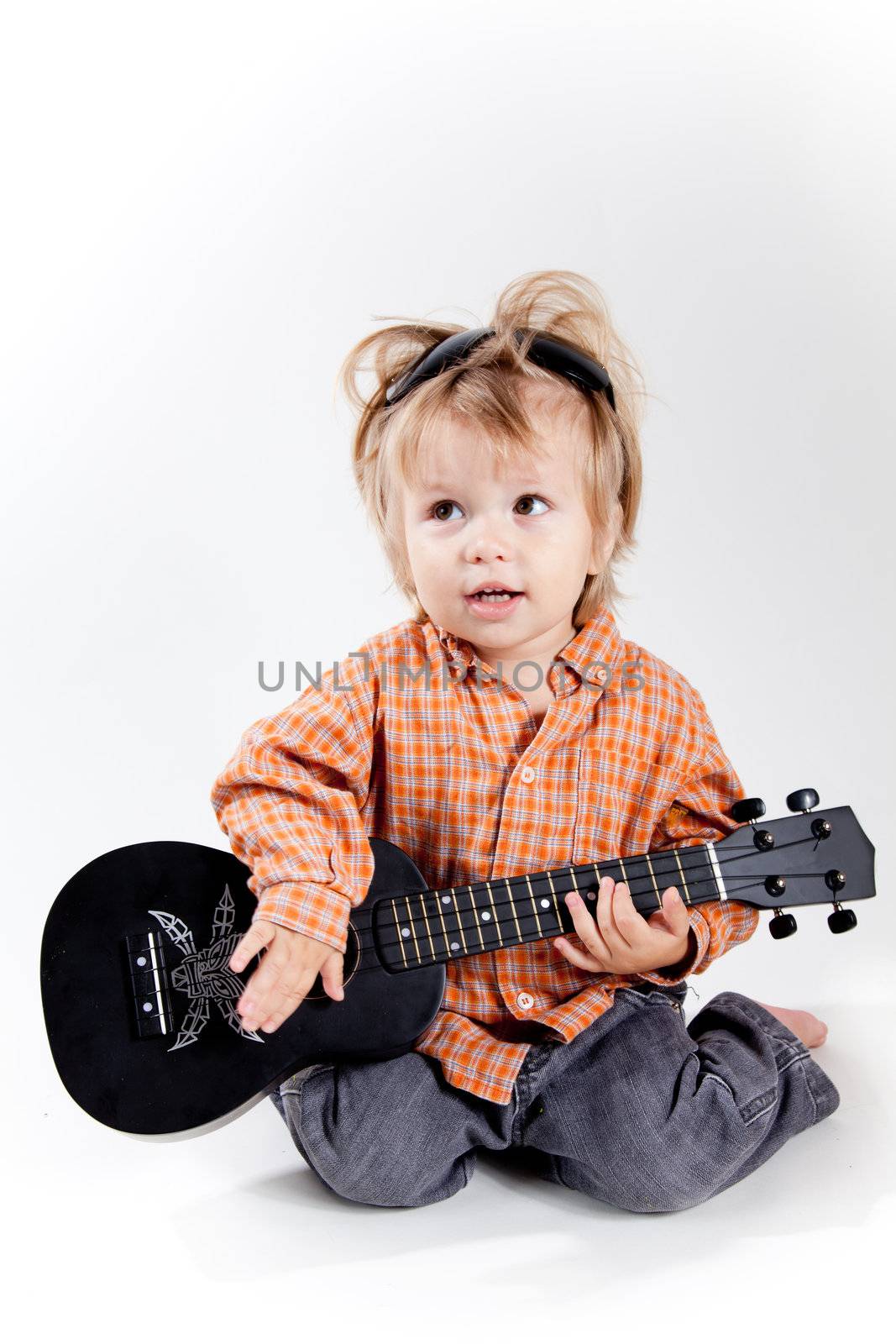 Cute little boy playing ukulele guitar, studio shot 