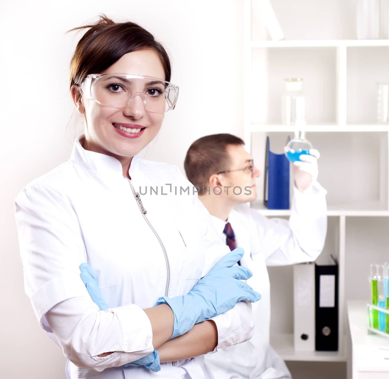 Three doctors are smiling at the camera in a doctors' office. Horizontally framed shot.