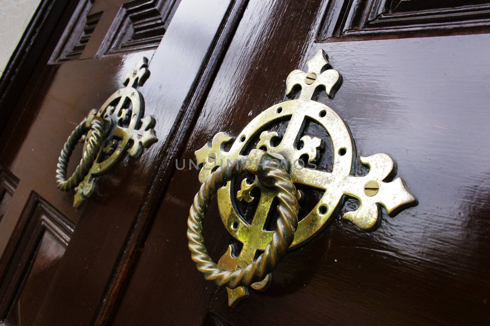 Old metal door handle knockers on a wooden door
