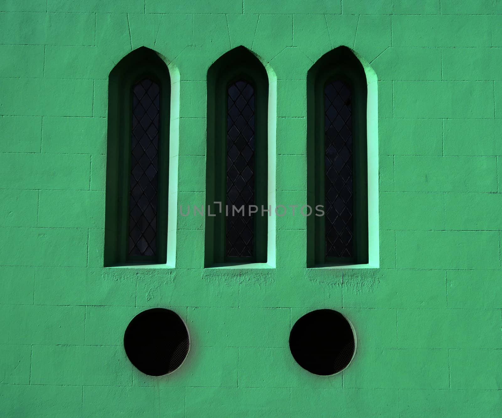 Three gothic windows on a green wall