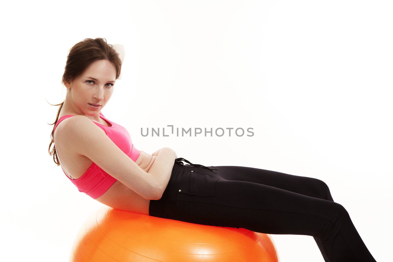 young woman workout on a orange fitness ball on white background