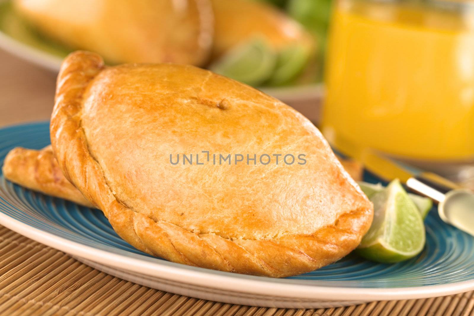 Peruvian snack called Empanada (pie) filled with chicken and beef served with limes (Selective Focus, Focus on the middle front part of the empanada)