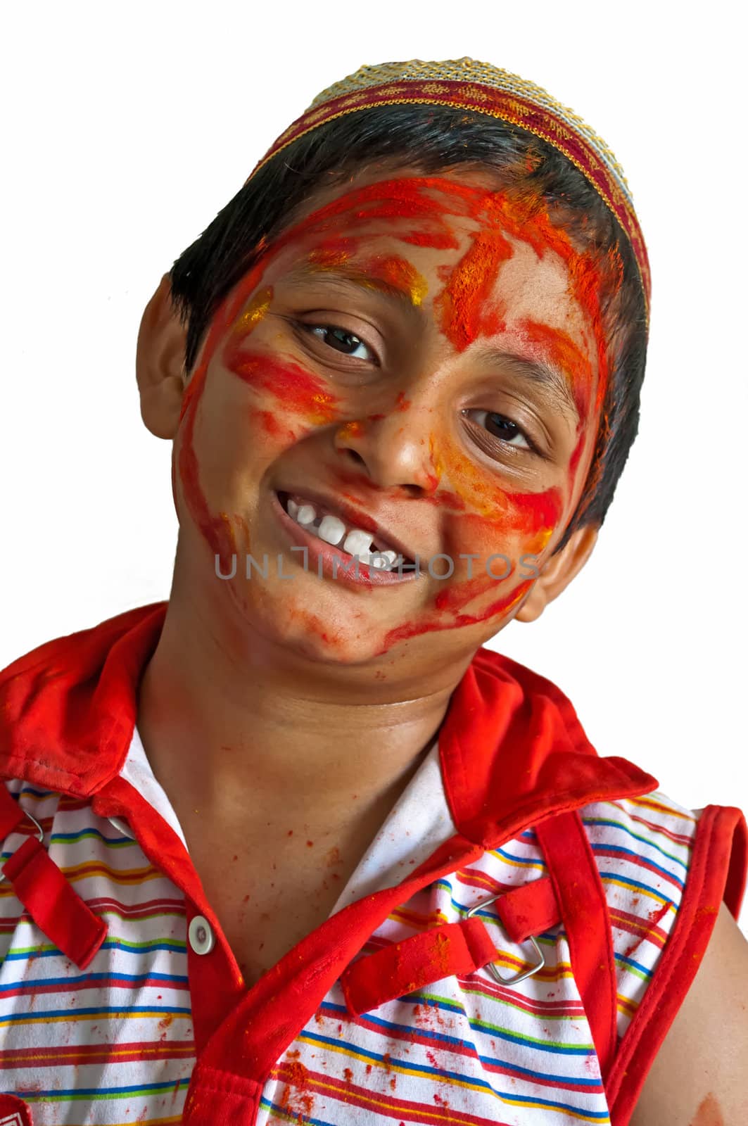 Young boy playing Holi, smiling with colors on face with cap