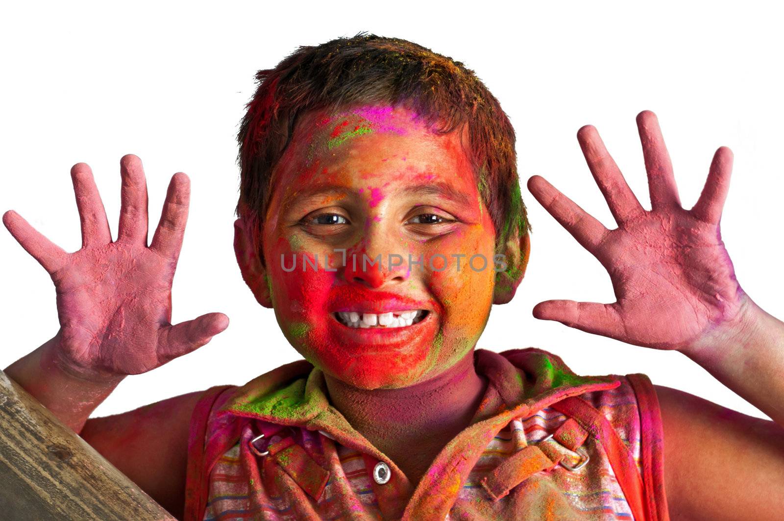 Close up face of young boy playing Holi, smiling with colors on face and hands