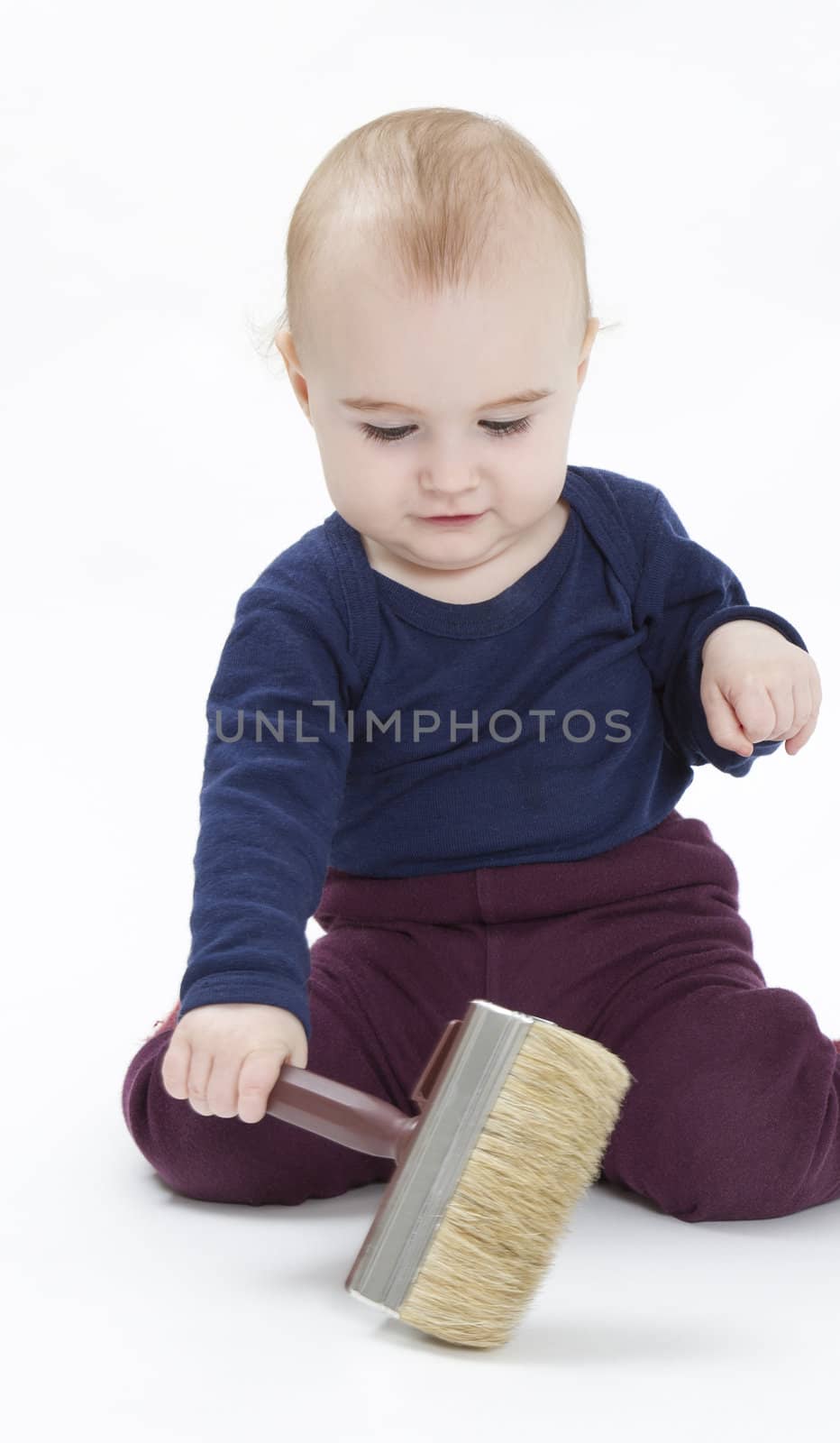 young child in blue shirt with brush on light background